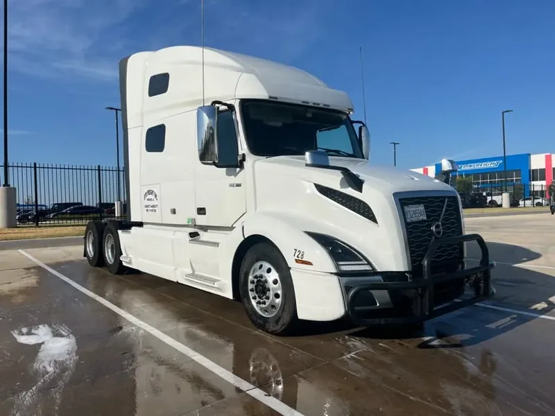 White Volvo VNL sleeper on a wet lot after a mobile truck wash
