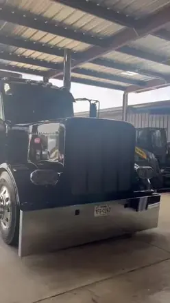 Black Peterbilt 389 washed under a shop canopy